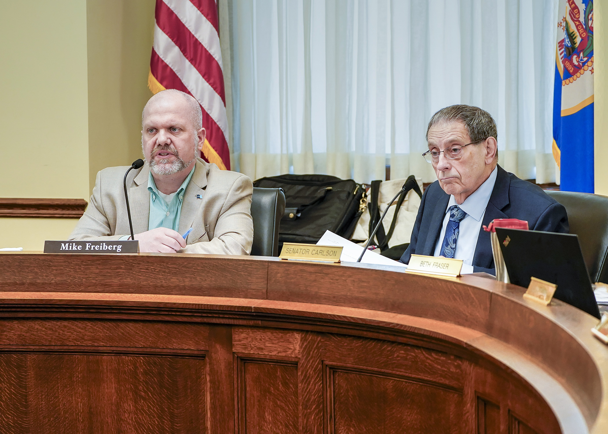 Rep. Mike Freiberg and Sen. Jim Carlson listen to a walk-through of differences between the House and Senate election policy bills during the first conference committee meeting. (Photo by Andrew VonBank)